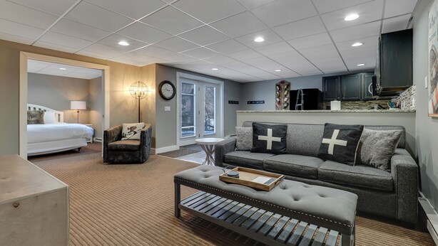 A modern hotel room with a bed, a sofa, a coffee table, and a dining area. - 2BR Slopeside Disciples Village 691 - Amazing Ski In/Ski Out on Boyneland! (Boyne Falls)