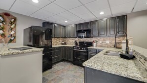 A modern kitchen with granite countertops, stainless steel appliances, and dark cabinetry. - 2BR Slopeside Disciples Village 691 - Amazing Ski In/Ski Out on Boyneland! (Boyne Falls)
