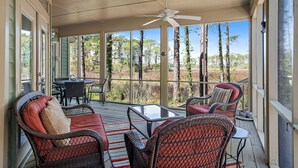 A covered porch with wicker furniture, a table, and a ceiling fan. - Gated Resort ~ Golf Cart ~ Outdoor Deck (Miramar Beach)