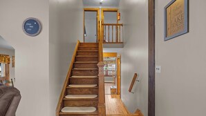 Un escalier en bois avec une rampe, une enseigne encadrée accrochée au mur et une enseigne circulaire avec du texte.