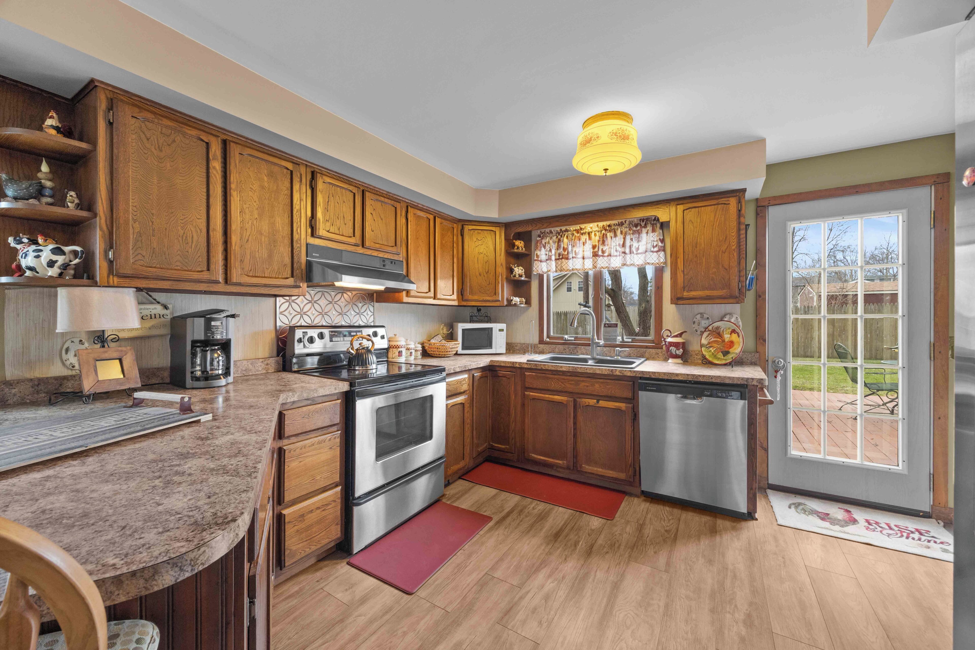 A kitchen with wooden cabinets, stainless steel appliances, and a large window.