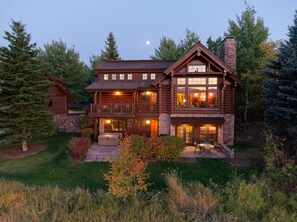 A large log cabin with a balcony, a hot tub, and a fireplace.