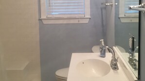 A bathroom with a white sink, a mirror, and a window with blinds. - Grace's Getaway: Newly refurbished.Two blocks to the beach! (Jekyll Island)