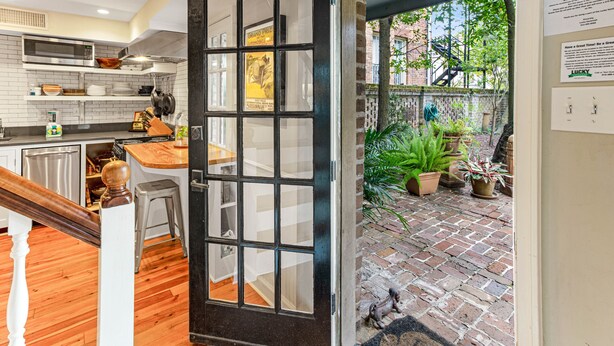 A modern kitchen with a wooden staircase, a view of the garden, and a door leading to an outdoor area.