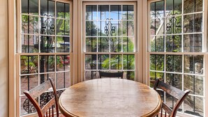 A round wooden table with four chairs in a room with large windows.
