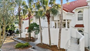 A residential building with white exterior walls, red-tiled roofs, and a staircase leading to the entrance. - 4BR Beach Villa with TWO GOLF CARTS!  Near Pool & Beach Tram. Screened Porch. (Miramar Beach)
