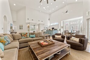 Ein geräumiges Wohnzimmer mit einer großen Eckcouch, einem Couchtisch und einem Essbereich im Hintergrund.