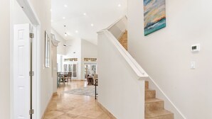 A spacious hallway with a staircase leading to a dining area. - 4BR Beach Villa with TWO GOLF CARTS!  Near Pool & Beach Tram. Screened Porch. (Miramar Beach)