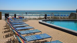Un espace piscine avec des chaises longues et vue sur la plage.