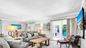 Una sala de estar moderna con un conjunto de sofá, una mesa de centro y un televisor montado en la pared.