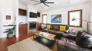 A modern living room with a leather sofa, a wooden coffee table, a fireplace, and a ceiling fan.