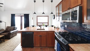 A modern kitchen with wooden cabinets, a built-in dishwasher, a stove, and a microwave.