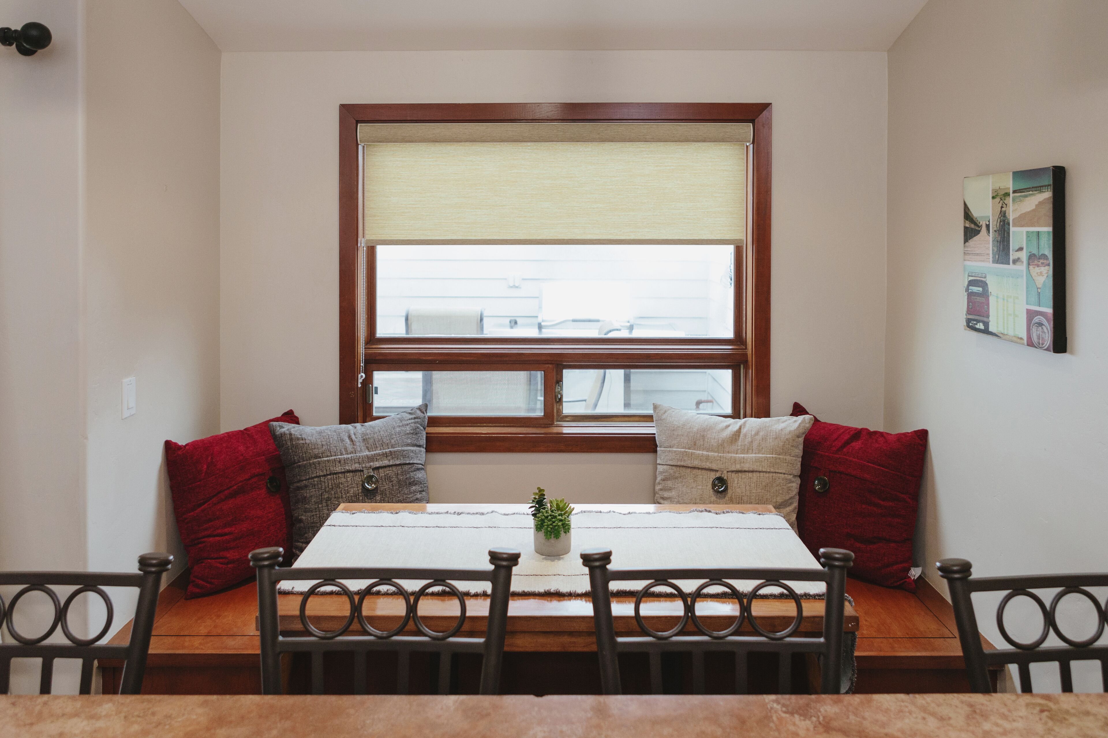 A dining area with a wooden table, four chairs, and a bench with cushions.