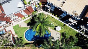 An aerial view of a residential area with a swimming pool surrounded by palm trees and a small garden. - Balcones del Pacifico 21, pool, and Private rooftop access in the heart of town! (Tamarindo)