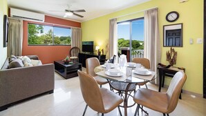 A modern living room with a sofa, a dining table set for four, and a television. - Balcones del Pacifico 21, pool, and Private rooftop access in the heart of town! (Tamarindo)