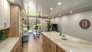 Una cocina moderna con armarios de madera, encimera de mármol y vistas a un patio exterior.