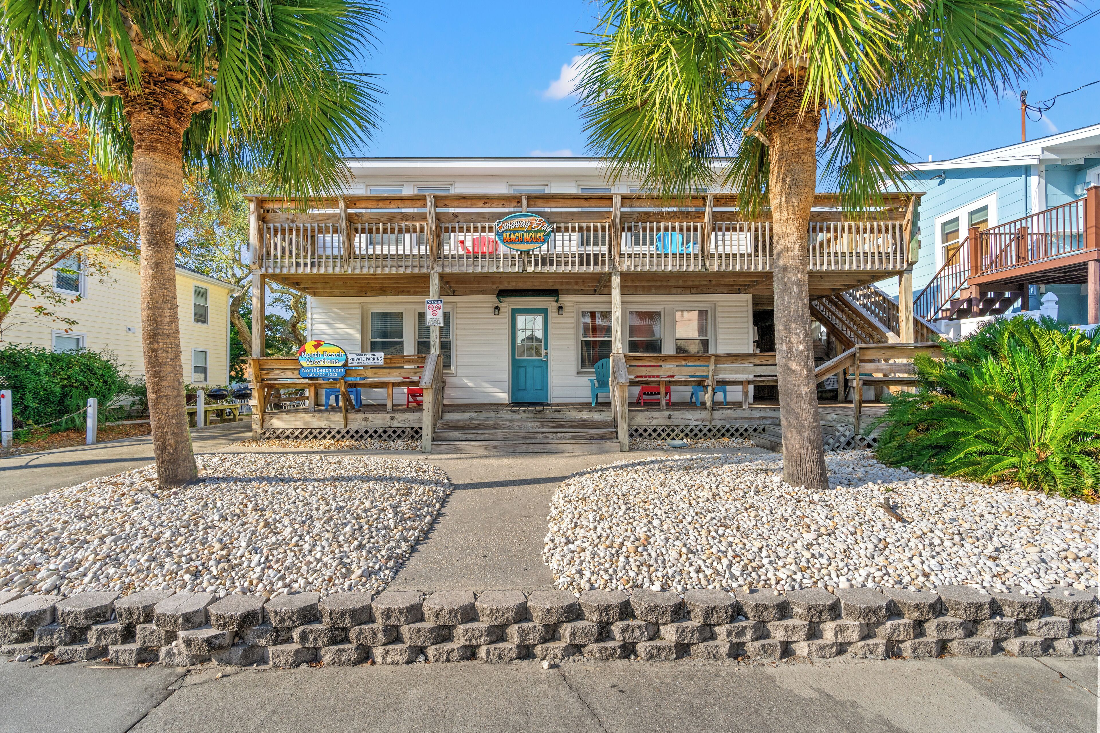 Un bâtiment situé en bord de mer, doté d’une terrasse en bois et d’une enseigne indiquant « Bar et grill en bord de mer ».