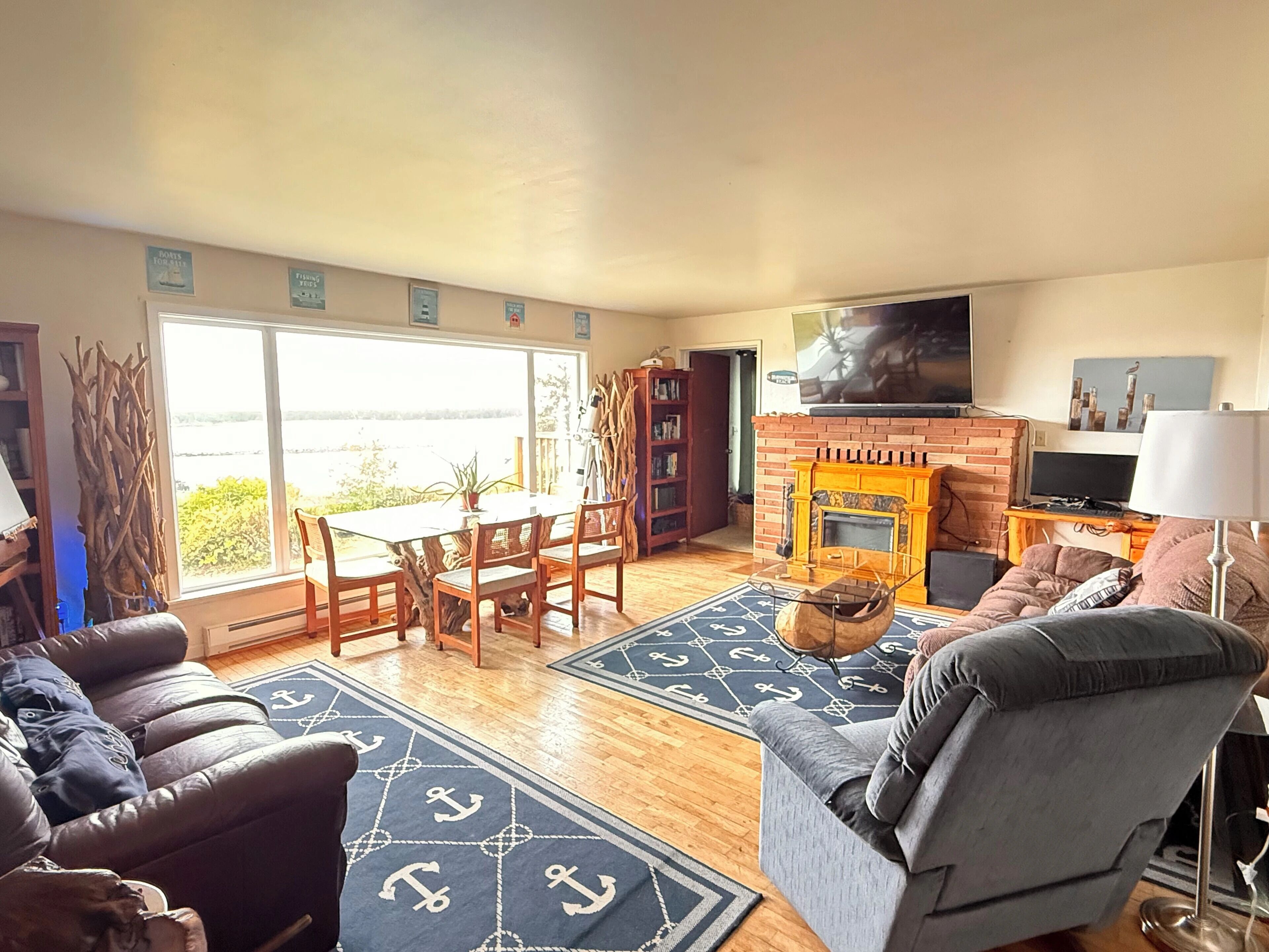 A living room with a fireplace, a television, a sofa, a coffee table, and a dining area with a table and chairs.