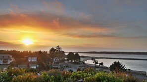 A coastal landscape with a sunset, houses, and a body of water.