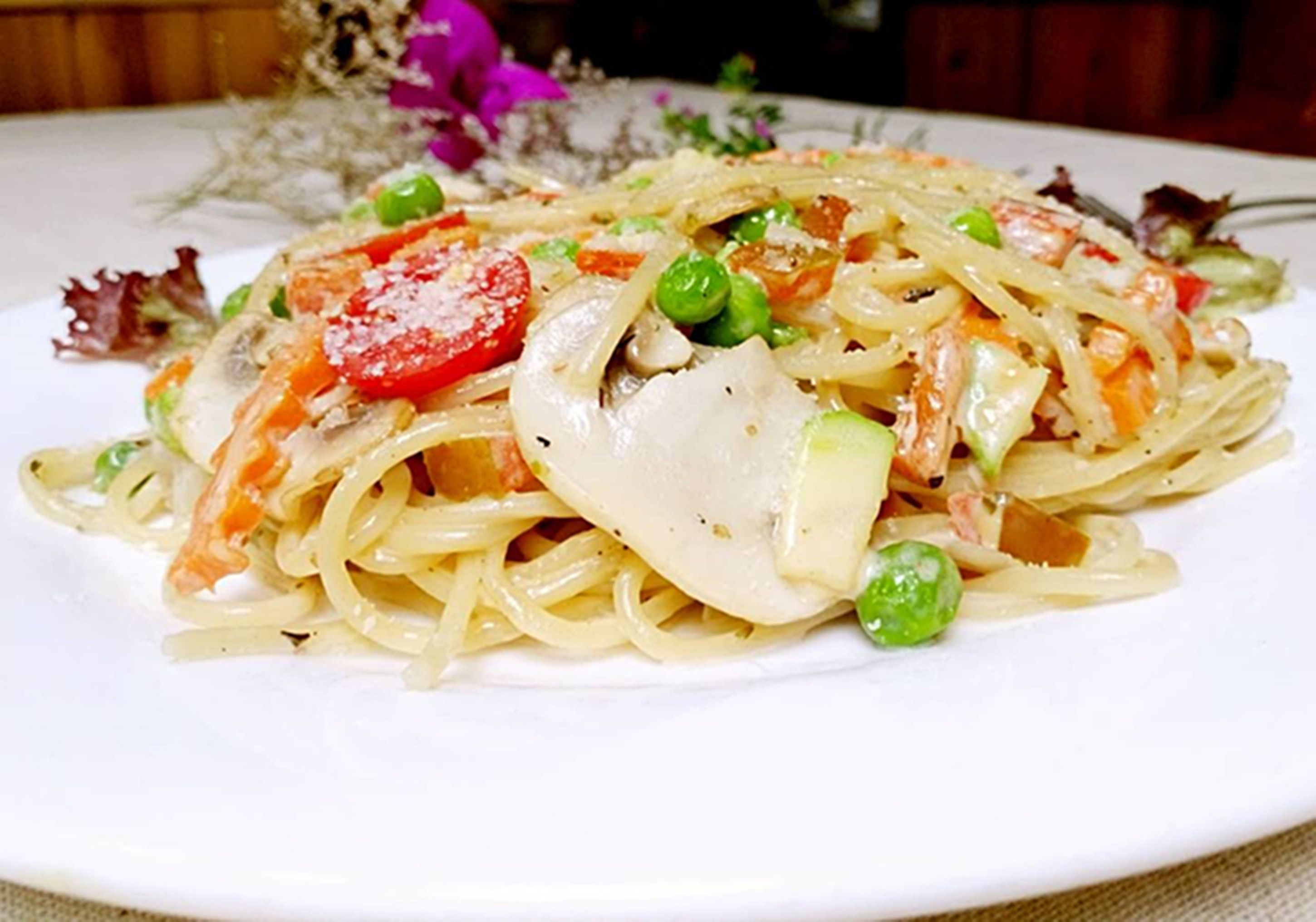 A plate of pasta with vegetables and cheese.