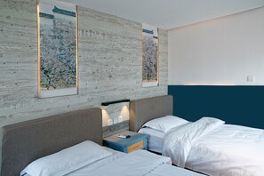 Ein Hotelzimmer mit zwei Betten, einem Nachttisch und zwei an der Wand befestigten Kunstwerken.