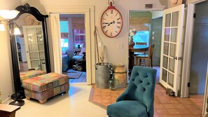 Relax in this inviting living room with a comfortable armchair, colorful ottoman, and large mirror.