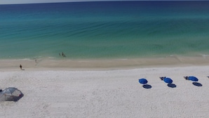 A beach with clear turquoise water, a sandy shore, and a few umbrellas.