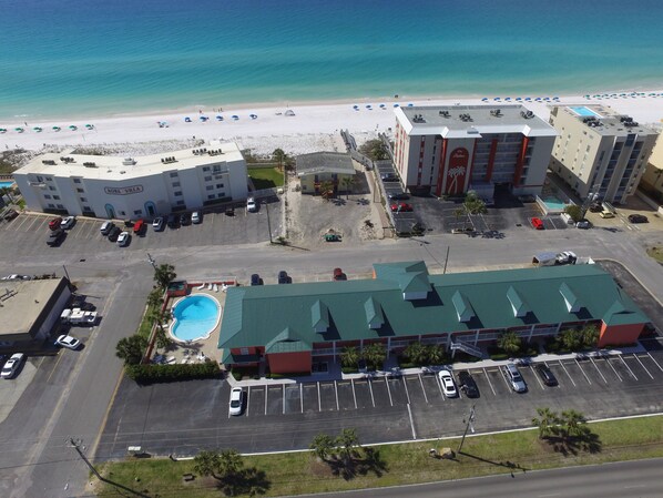 Vista aérea de um hotel com piscina, estacionamento e vista para a praia.