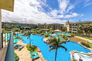 Ein Resort mit mehreren Schwimmbecken, Palmen und blauem Himmel.