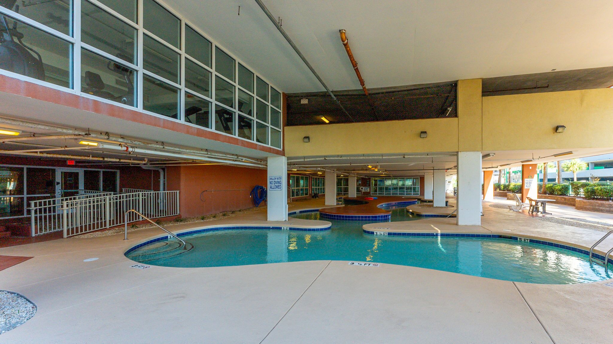 Ein Poolbereich mit mehreren Pools, einer überdachten Sitzgelegenheit und Blick auf die Außenansicht des Gebäudes.