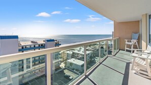 A balcony with a clear view of the ocean and beach, glass railings, and white outdoor furniture. - Luxury condo, across the street from the beach + Free Attraction Tickets! (North Myrtle Beach)
