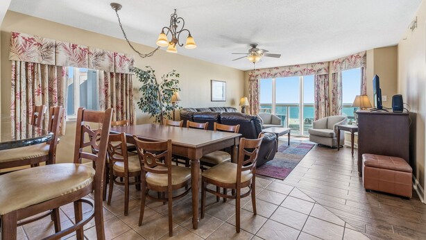 A spacious living area with a dining table, chairs, a sofa, and a ceiling fan. - Luxury condo, across the street from the beach + Free Attraction Tickets! (North Myrtle Beach)