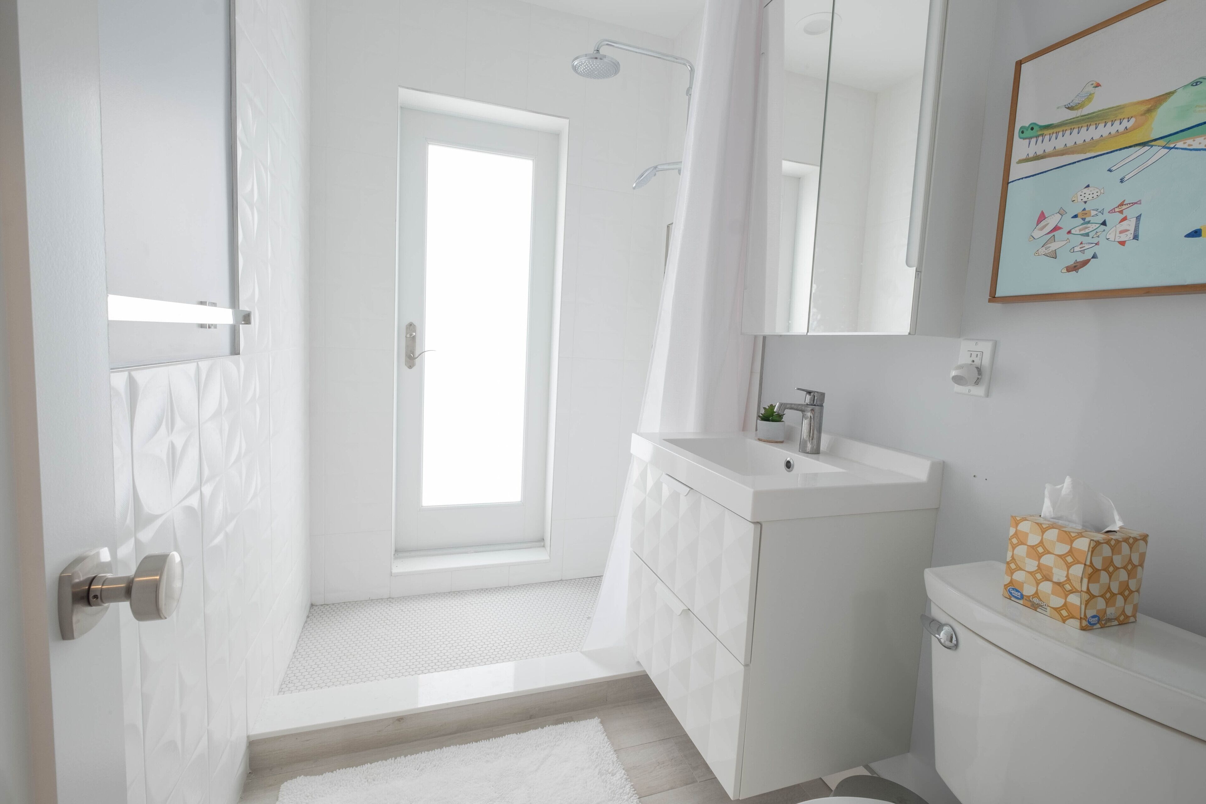 A modern bathroom with a shower, toilet, and sink.