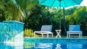 A pool with clear blue water, two lounge chairs, a small table, and a decorative fountain. - Beach, Art District, Shopping, Restaurants! Best Spa in Delray! (Delray Beach)