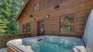 Una cabaña de madera con jacuzzi en la terraza.