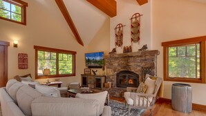 Un salón acogedor con chimenea de piedra, asientos cómodos y amplios ventanales con vistas al exterior.