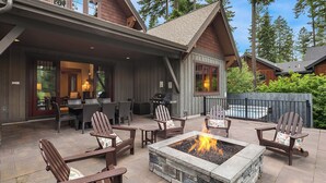 Eine Terrasse im Freien mit Feuerstelle, Holzstühlen und einem Essbereich mit Tischen und Stühlen.