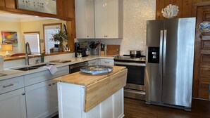 A modern kitchen with white cabinets, a stainless steel refrigerator, and a wooden island. - 3 Bedroom, 2 full baths. Steps to beach! (Kill Devil Hills)
