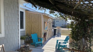 A wooden deck with two turquoise chairs and a bench, surrounded by potted plants. - 3 Bedroom, 2 full baths. Steps to beach! (Kill Devil Hills)