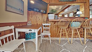 A wooden interior with a bar area, white chairs, a table, and a TV mounted on the wall. - 3 Bedroom, 2 full baths. Steps to beach! (Kill Devil Hills)
