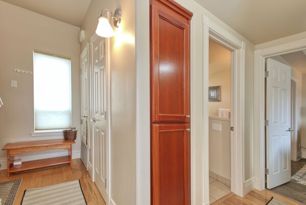 A hallway with a wooden bench, a door, and a wall-mounted light fixture.