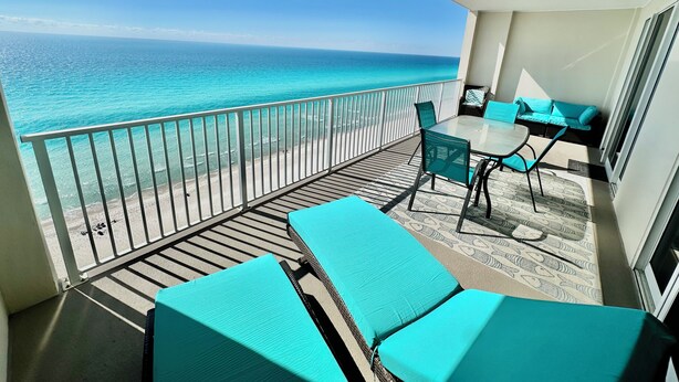 Een balkon met uitzicht op de oceaan, een tafel met stoelen en een bank.