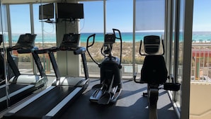 A gym with treadmills, an elliptical, and a stationary bike, overlooking a beach. - Wilson's Beach Dream: Gulf Front 5 Star 3BR 3Bath with Beach Service (Navarre)