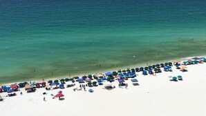 A beach with clear turquoise water, white sand, and numerous umbrellas and beach chairs. - Wilson's Beach Dream: Gulf Front 5 Star 3BR 3Bath with Beach Service (Navarre)