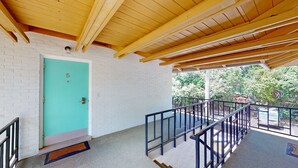 A building with a turquoise door, white brick walls, and a wooden ceiling. - Atlantic Breeze #5 2 bedrooms, 2 bathrooms (Jekyll Island)