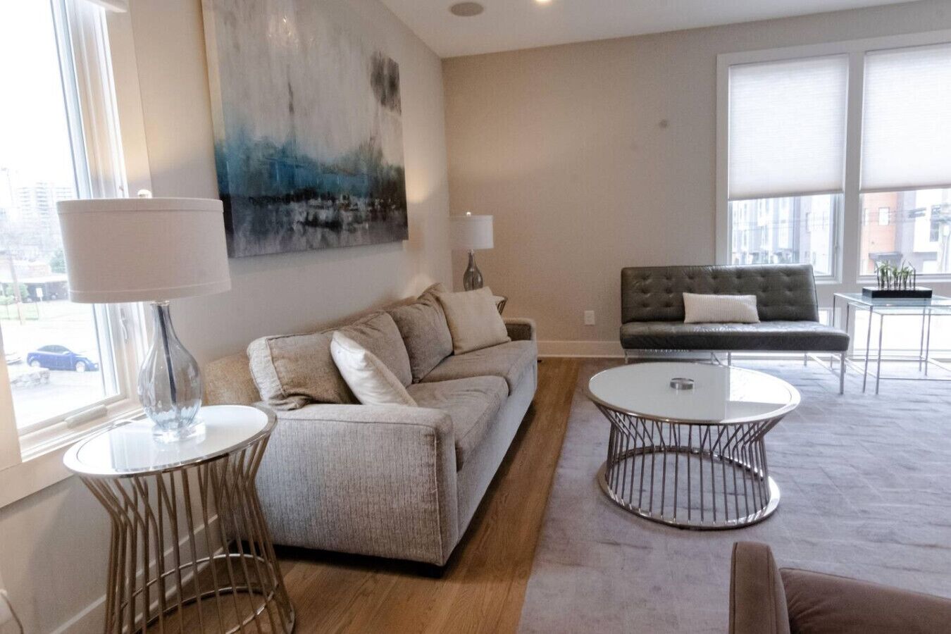A modern living room with a sofa, a round coffee table, and a painting on the wall.
