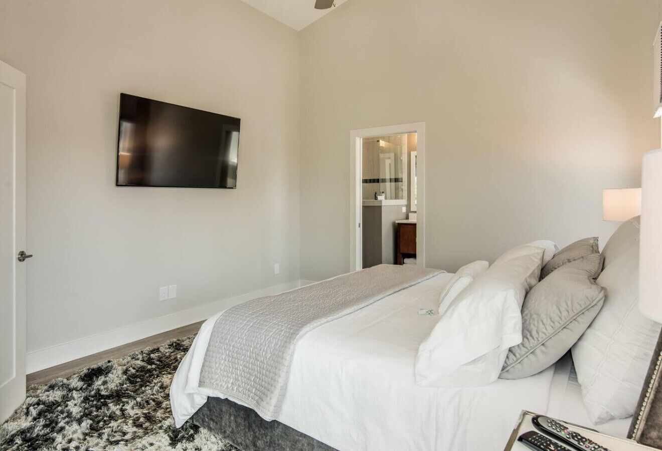 Une chambre à coucher avec un lit, un téléviseur à écran plat, un miroir et une porte.