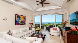 A spacious living room with a white sofa set, a coffee table, and a large painting on the wall. - Matapalo 606♆ Amazing Ocean views on the center of town ♆ (Tamarindo)