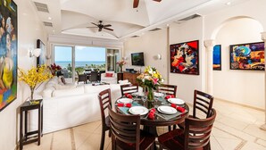A dining area with a round table set for six, a ceiling fan, and artwork on the walls. - Matapalo 606♆ Amazing Ocean views on the center of town ♆ (Tamarindo)