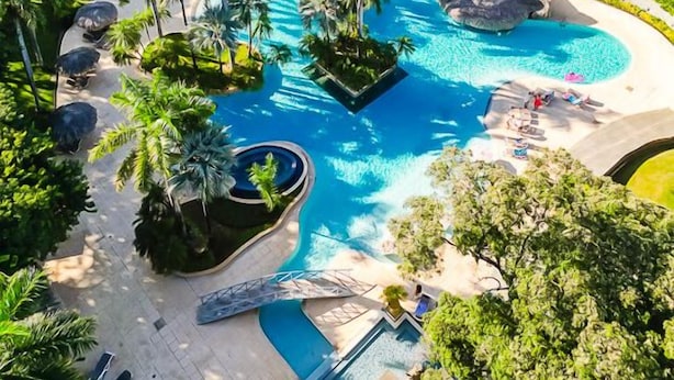 A resort with a large central pool, palm trees, and a view of the ocean. - Matapalo 606♆ Amazing Ocean views on the center of town ♆ (Tamarindo)